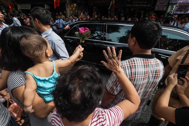 Một cháu bé cầm một bông hoa vẫy chào tạm biệt chiếc xe chở Tổng thống Pháp Francois Hollande
