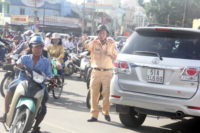 Cảnh sát giao thông hướng dẫn người dân đi qua khu vực có rào chắn - Ảnh: Q.KHẢI