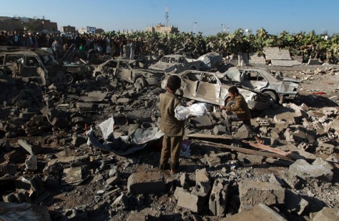 Người dân Yemen đứng tại một địa điểm vừa bị không kích bởi liên minh do Saudi dẫn đầu - Ảnh: AFP