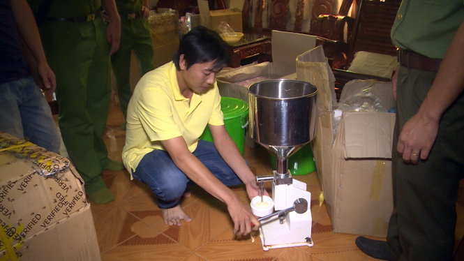 Ông Nguyễn Văn Giáp (ngồi) đang thực nghiệm quy trình ép, sản xuất mỹ phẩm giả với sự chứng kiến của cơ quan công an. Ảnh: Quỳnh Giang.