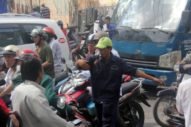 Một người gom rác điều tiết giao thông, ngăn không cho người đi ngược chiều trên đường Nguyễn Thái Sơn - Ảnh: Q.KHẢI