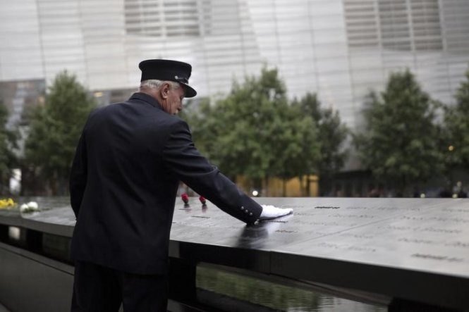 Một cựu nhân viên sở cứu hỏa New York đặt tay lên bảng tưởng niệm các nạn nhân vụ khủng bố 11-9 - Ảnh: Reuters