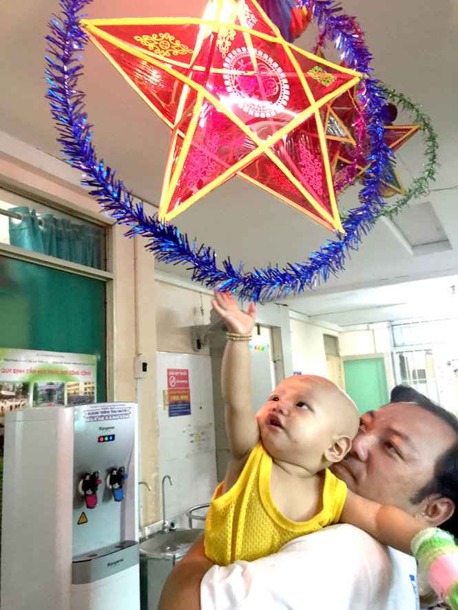 Bệnh nhi Nguyễn Chí Vỹ (9 tháng tuổi, quê ở An Giang), điều trị tại Bệnh viện Ung bướu  TP.HCM thích thú chiếc lồng đèn ông sao trang trí ở hành lang khoa nhi - Ảnh: TỐ OANH