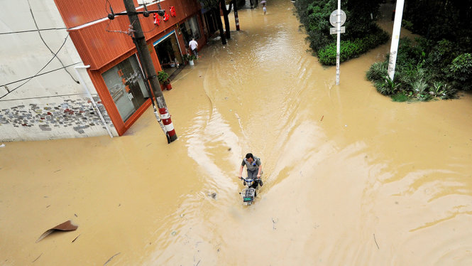 Một người đàn ông chạy xe trên đường phố ngập đầy nước ở thành phố Phúc Châu, tỉnh Phúc Kiến - Ảnh: Reuters