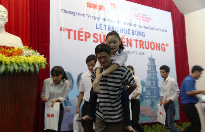 Tân sinh viên khuyết tật Trần Thị Diệu Thanh được ba cõng đến nhận học bổng - Ảnh: MINH AN