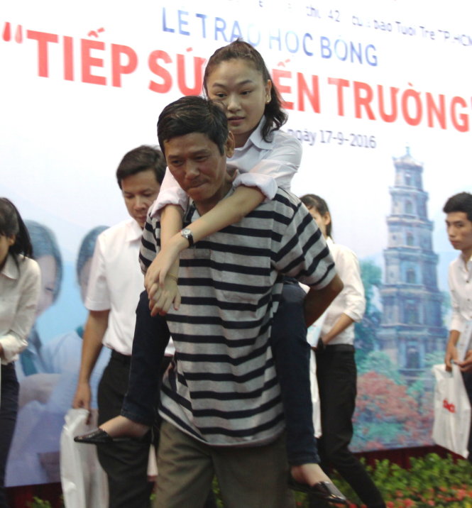 Trần Thị Diệu Thanh, tân sinh viên Trường cao đẳng Công nghiệp Huế, được cha cõng lên sân khấu nhận học bổng. Thanh bị bại liệt nên suốt 12 năm trường đi học trên lưng cha - Ảnh: MINH AN