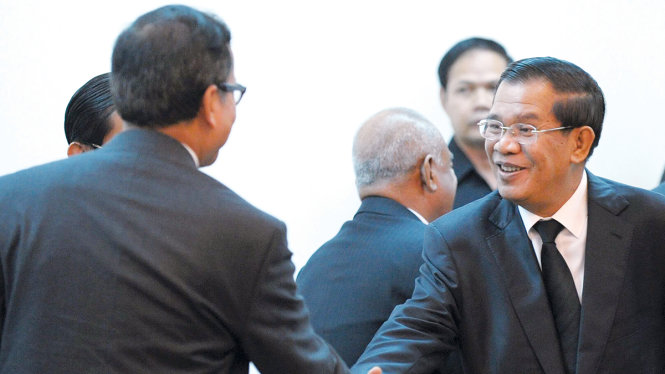 Thủ tướng Campuchia Hun Sen (phải) bắt tay thủ lĩnh đối lập Sam Rainsy khi hai bên hòa hoãn - Ảnh: AFP