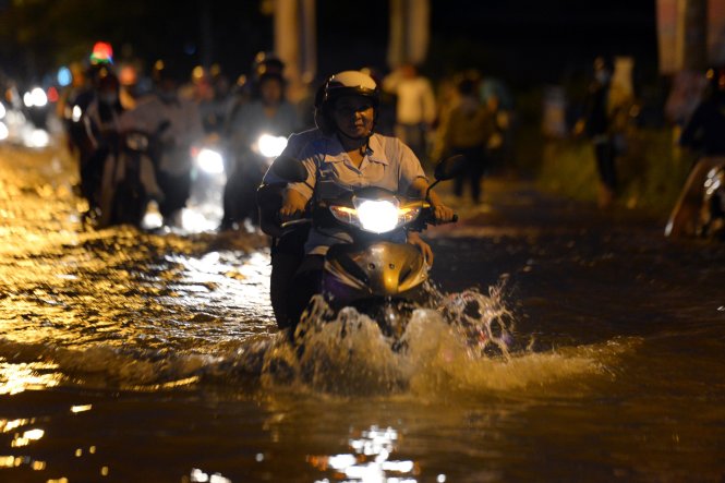 Nước ngập sâu đến bánh xe trên đường Lê Văn Lương - Ảnh: HỮU KHOA