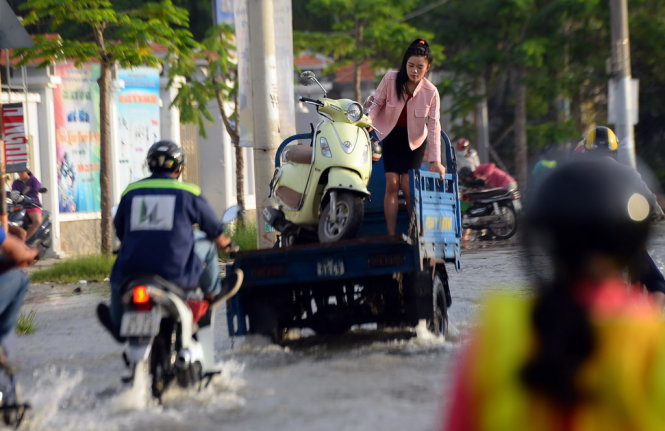 Nhiều người thuê xe ba gác chở xe máy qua đoạn ngập nước - Ảnh: HỮU KHOA