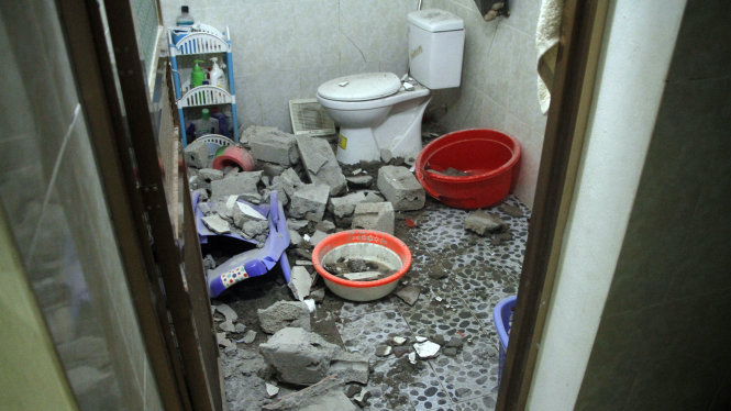 Phòng vệ sinh bị thủng một mảng tường lớn, gạch ngổn ngang dưới sàn - Ảnh: ĐỨC HIẾU