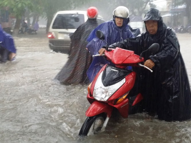 Nước vào động cơ làm nhiều xe máy bị chết máy trên đường Nguyễn Huệ (TP Huế) - Ảnh: NHẬT LINH