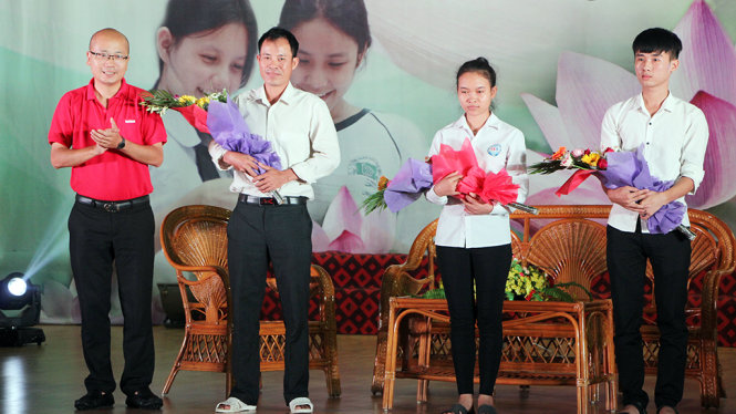 Ông Dương Đức Đà Trang, Trưởng văn phòng đại diện miền Bắc báo Tuổi trẻ tặng hoa động viên hai tân sinh viên Lê Thị Hồng và Nguyễn Huỳnh Đức - Ảnh: DOÃN HÒA