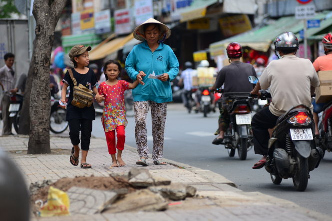 Bà Thạnh và hai đứa cháu gái bán vé số trên hè phố Sài Gòn - Ảnh: D.P.
