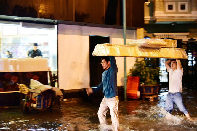 Nước ngập khiến giao thông trên đường Trường Sơn ùn ứ, nhiều người phải vác hàng hoá đi bộ ra sân bay - Ảnh: HỮU THUẬN