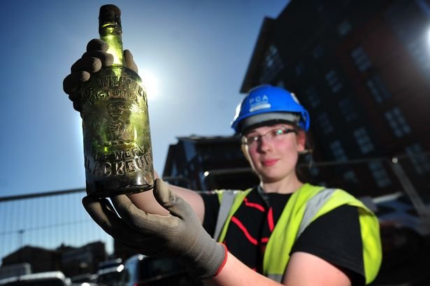 Nhà khảo cổ Rosie Banens với một chai rượu còn nguyên được tìm thấy tại khu vực chuẩn bị xây dựng tòa nhà 13 tầng ở Manchester - Ảnh: Manchester Evening News