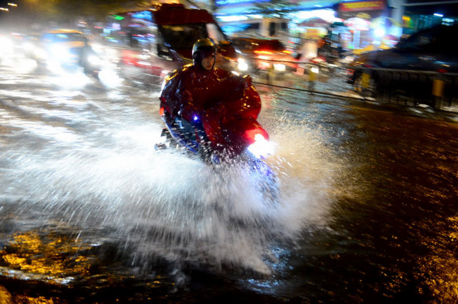 Một xe máy chạy bắn tung nước trên đoạn đường ngập trên đường Đinh Tiên Hoàng, Q. Bình Thạnh, TP.HCM tối 27-9 - Ảnh: QUANG ĐỊNH