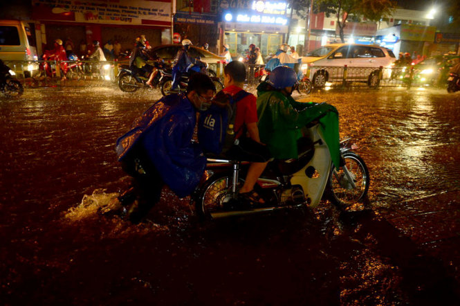 Một xe máy phải đẩy qua đoạn đường ngập trên đường Đinh Tiên Hoàng, Q. Bình Thạnh, TP.HCM tối 27-9 - Ảnh: QUANG ĐỊNH