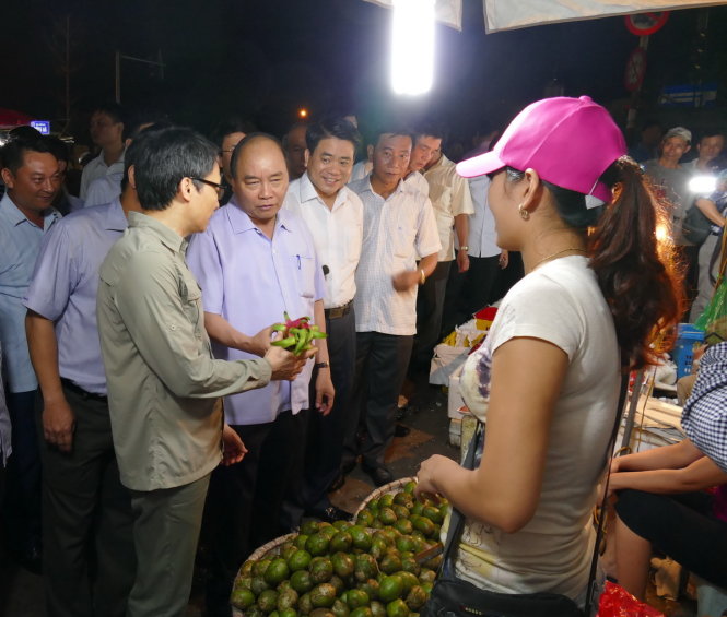 Chủ tịch UBND TP Hà Nội Nguyễn Đức Chung cũng xuất hiện sau khi Thủ tướng có mặt tại chợ Long Biên, cùng Thủ tướng thăm hỏi chị Hải - một người bán lẻ trái cây gần cổng chợ - Ảnh: LÊ KIÊN