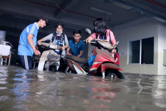 Sinh viên lội nước mang xe ra khỏi hầm sau một đêm bị ngâm trong nước tại hầm giữ xe ký túc xá ĐH Quốc gia TP do cơn mưa lớn chiều 26-9 - Ảnh: NGỌC HIỂN