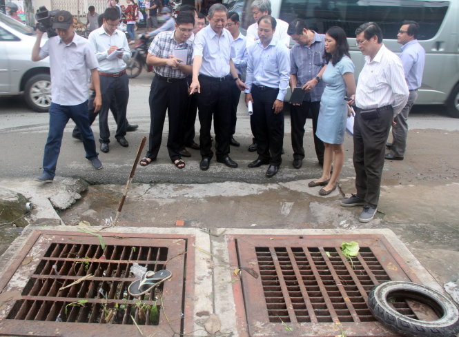 Ông Lê Văn Khoa - phó chủ tịch UBND TP (chỉ tay) kiểm tra vị trí miệng hố ga thoát nước trên đường Lã Xuân Oai bị lấn chiếm và xả rác - Ảnh: Q.KHẢI