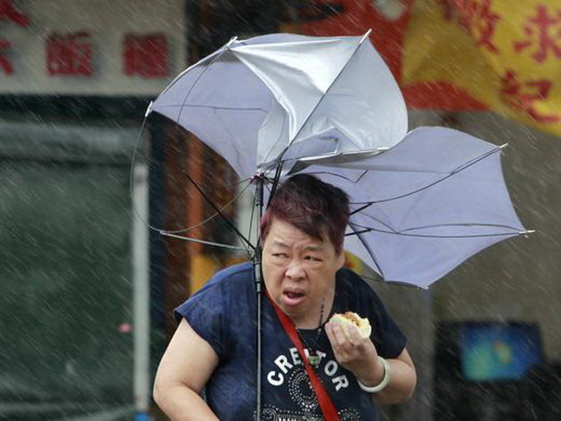 Một phụ nữ chống chọi với gió lớn trên đường phố Đài Loan ngày 27-9 - Ảnh: EPA
