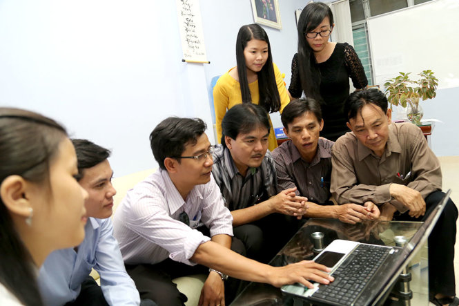 Ban giám hiệu cùng giáo viên Trường THPT Nguyễn Du, Q.10, TP.HCM xem thông tin về việc công bố phương án thi THPT quốc gia năm 2017 trên Tuổi Trẻ Online - Ảnh: NHƯ HÙNG
