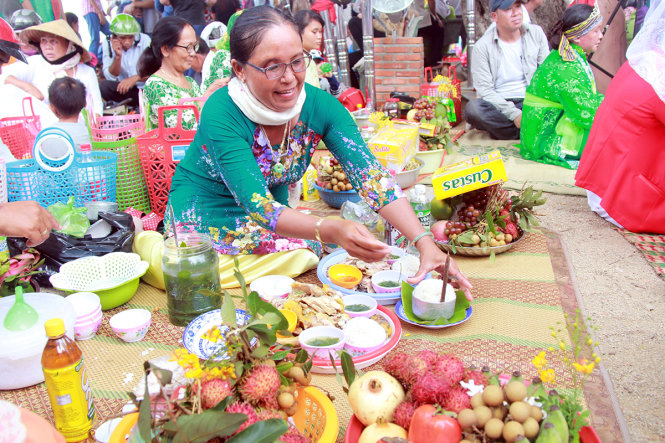 Một phụ nữ Chăm bày biện lễ vật dưới chân tháp Pô Klong Garai - Ảnh: TRUNG TÂN