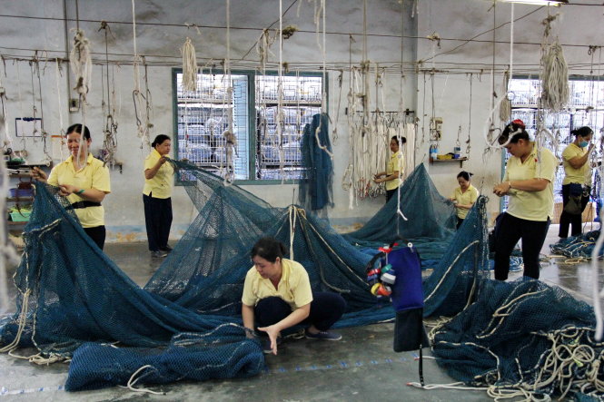Một nhóm thợ làm sạch lưới bằng cách dùng búa, dao đập bể những cục bêtông dính trên mắt lưới - Ảnh: MẬU TRƯỜNG
