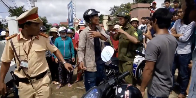 Hình ảnh người nhà của người vi phạm bị CSGT dùng còng số 8 còng tay trong quá trình cự cãi - Ảnh: T.B.D chụp lại.