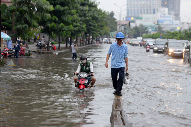 Nước ngập sâu trên đường Nguyễn Hữu Cảnh khiến người đi bộ phải di chuyern trên con lươn về nhà - Ảnh: HỮU KHOA
