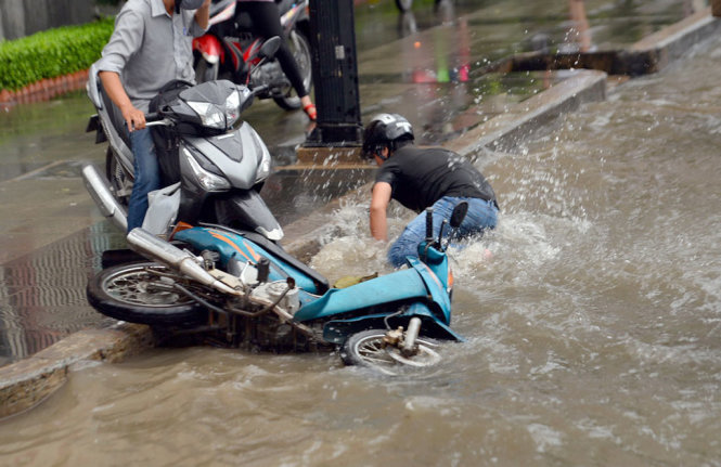 Một ngưới té ngã do đi qua đoạn ngập nước trên đường NGuyễn Hữu Cảnh - Ảnh: HỮU KHOA