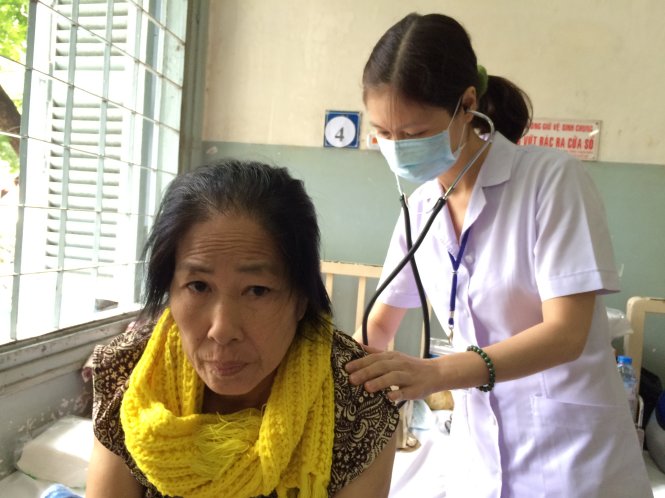 Nhân viên y tế kiểm tra sức khoẻ cho bà  Nguyễn Thị Thanh trong lúc chờ có thẻ BHYT để xạ trị  - Ảnh: L.TH.H.