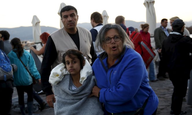 Một tình nguyện viên đưa một bé gái được cứu sống sau khi chiếc thuyền chở người tị nạn và di dân bị chìm gần đảo Lesbos của Hi Lạp - Ảnh: Reuters