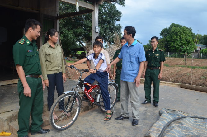 Thượng tá Nguyễn Hữu Phúc (thứ hai từ phải sang) trao xe đạp cho cậu học trò Trịnh Văn Sơn - Ảnh: V.N.