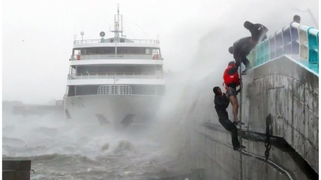 Các thành viên thủy thủ đoàn một chiếc phà đang đậu bị sóng cuốn đang được cứu lên bờ - Ảnh: AFP
