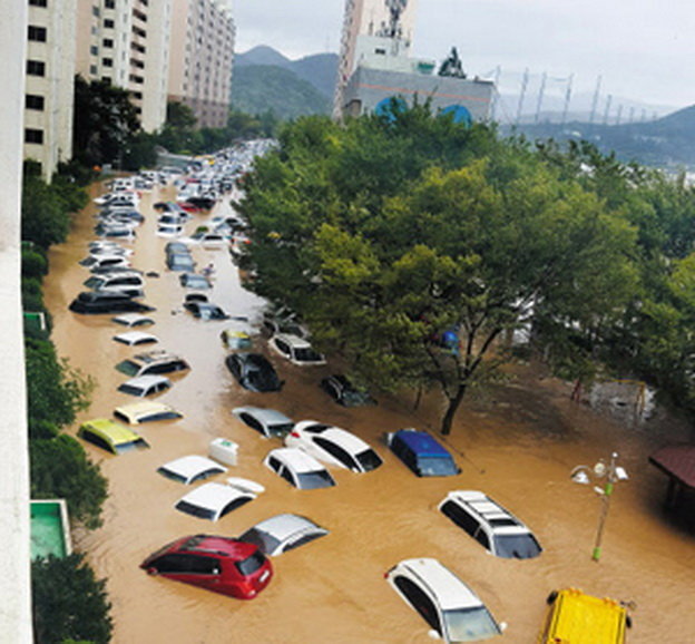 Ô tô trôi lềnh bềnh trong nước lũ - Ảnh: Chosun