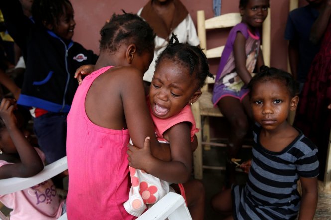 Một bé gái hoảng hốt khóc khi cùng người nhà sơ tán tới một ngôi trường đã bị bão phá hỏng - Ảnh: Reuters