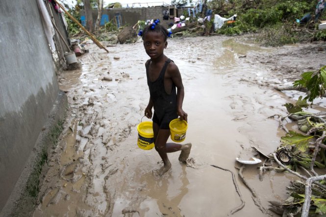 Một bé gái cố vét được ít nước dùng sau trận bão tại Les Cayes - Ảnh: AP
