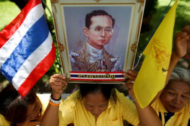 Người dân kính cẩn cầm ảnh nhà vua Bhumibol Adulyadej khi cầu sức khỏe cho ông bên ngoài bệnh viện Siriraj - Ảnh: REUTERS