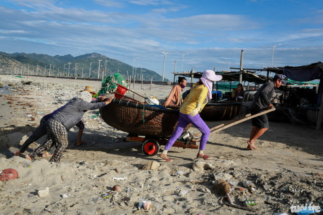 Một gia đình ở làng biển Thương Diêm 1 cùng đẩy thuyền thúng lên bờ - Ảnh: Tiến Thành