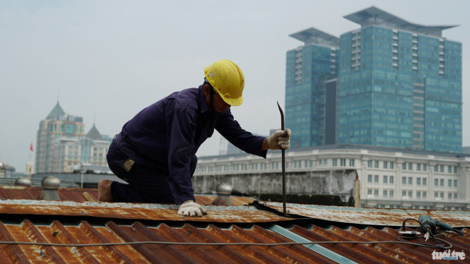 Công nhân bóc tách phần mái của thương xá Tax - Ảnh: Thuận Thắng