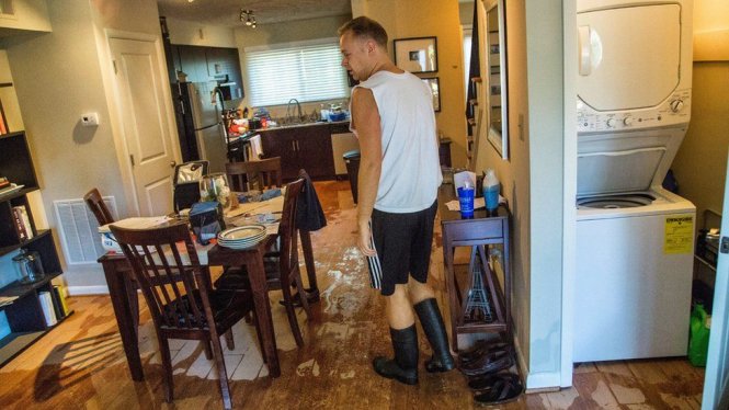 Anh Jeremy Spearman đang kiểm tra đồ đạc trong nhà bị nước tràn vào - Ảnh: AP