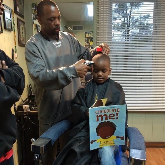Anh Ryan Griffin cắt tóc cho một bé trai trong lúc em đang đọc to cuốn sách cho bác thợ nghe - Ảnh: The Fuller Cut