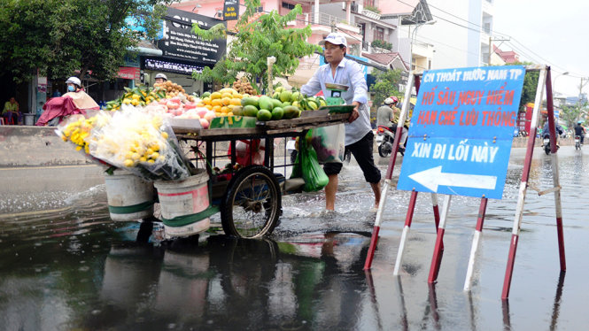 Một người dân đẩy xe qua khu vực bị ngập do triều trên đường Huỳnh Tấn Phát (Q.7)