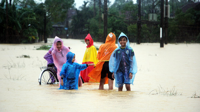 Nhóm trẻ ở xã Thạch Lâm, huyện Thạch Hà (Hà Tĩnh) mạo hiểm đi trên đường làng đã ngập đến đầu gối - Ảnh: DOÃN HÒA