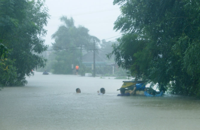 Người dân vật lộn trong mưa và nước ngập tại phường Đồng Sơn, TP Đồng Hới chiều 14-10 - Ảnh: ĐÌNH PHONG