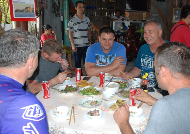 Nhóm du khách Úc phượt trên cung đường 14G bằng xe Minks đang giao lưu, ăn bữa cơm người Việt ở một ngôi nhà người Cơ Tu - Ảnh: V. HÙNG