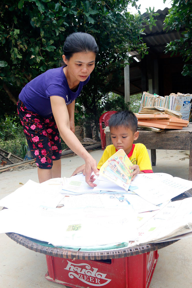 Mẹ con chị Cao Thị Hóa, ở thôn 3 xã Hương Đô, huyện Hương Khê, tỉnh Hà Tĩnh đang phơi sách trong sân nhà mình - Ảnh: THÁI LỘC