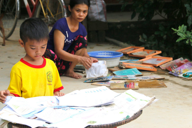 Hai mẹ con chị Cao Thị Hóa đang phơi và giặt sách trong sân nhà - Ảnh: THÁI LỘC