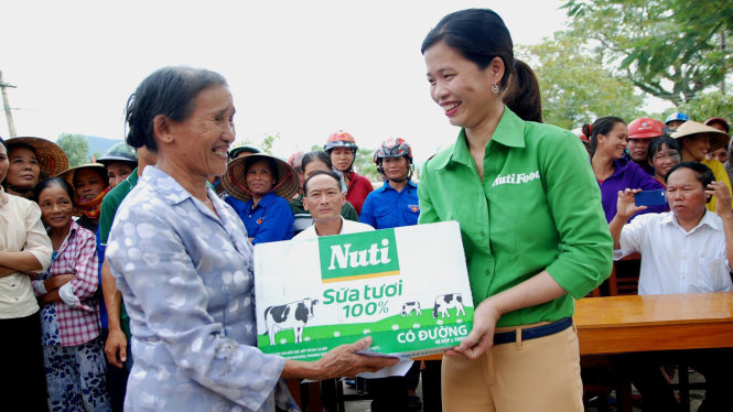 Đại diện công ty sữa Nutifood, đơn vị đồng hành cùng báo Tuổi trẻ tặng mỗi hộ dân vùng lũ Cao Quảng một thùng sữa – Ảnh: QUỐC NAM